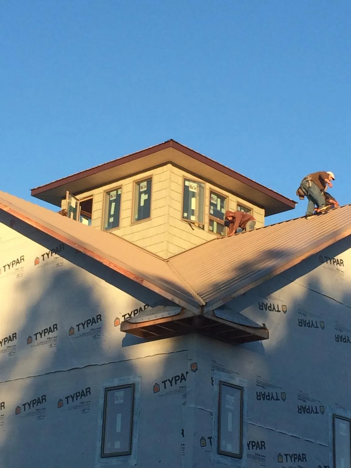 Roofers working around a rooftop cupola on a new metal roof at sunset — Roof Waterproofing in Winston by Roofing Brothers